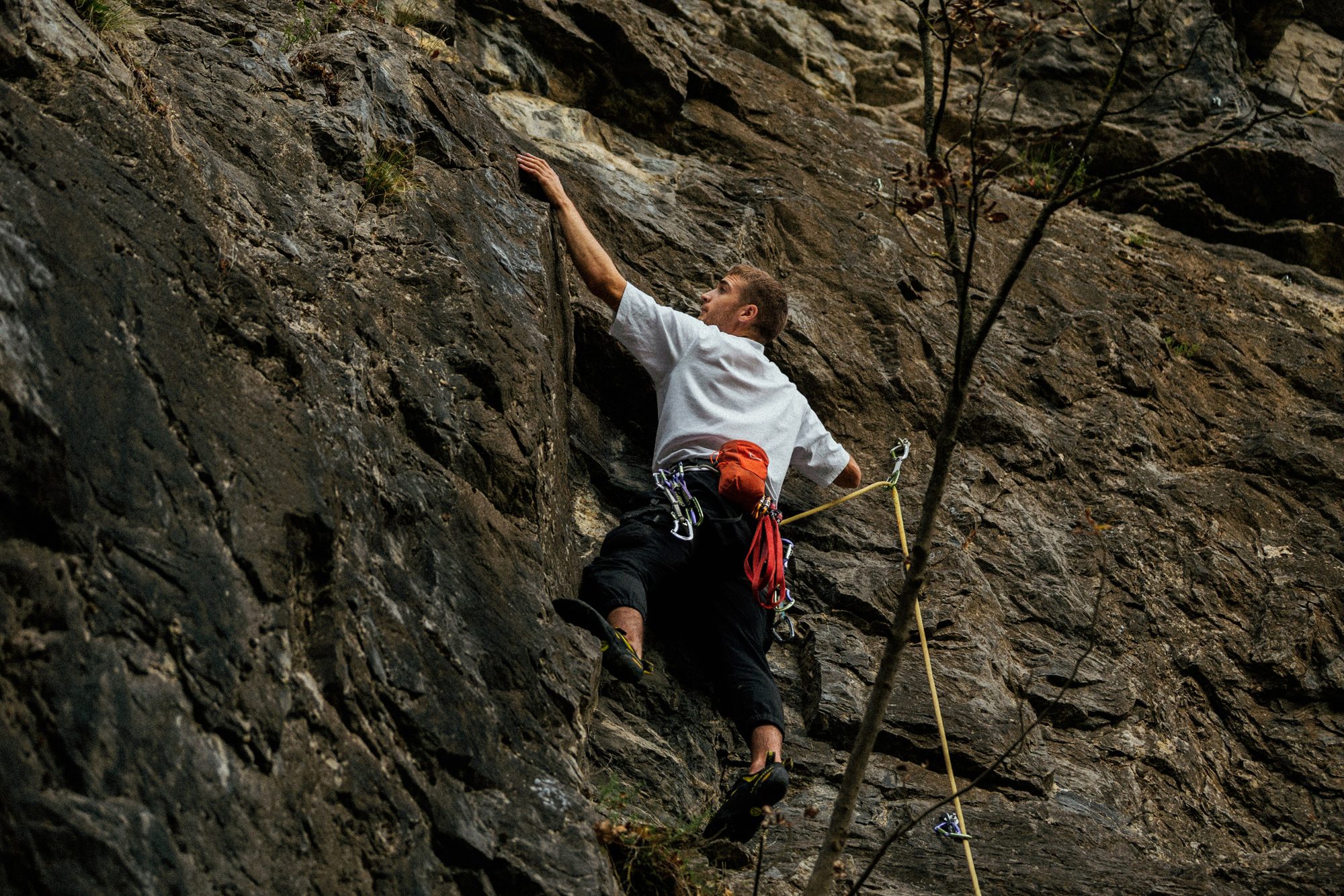 Climber in a white t-shirt on a dark rock face