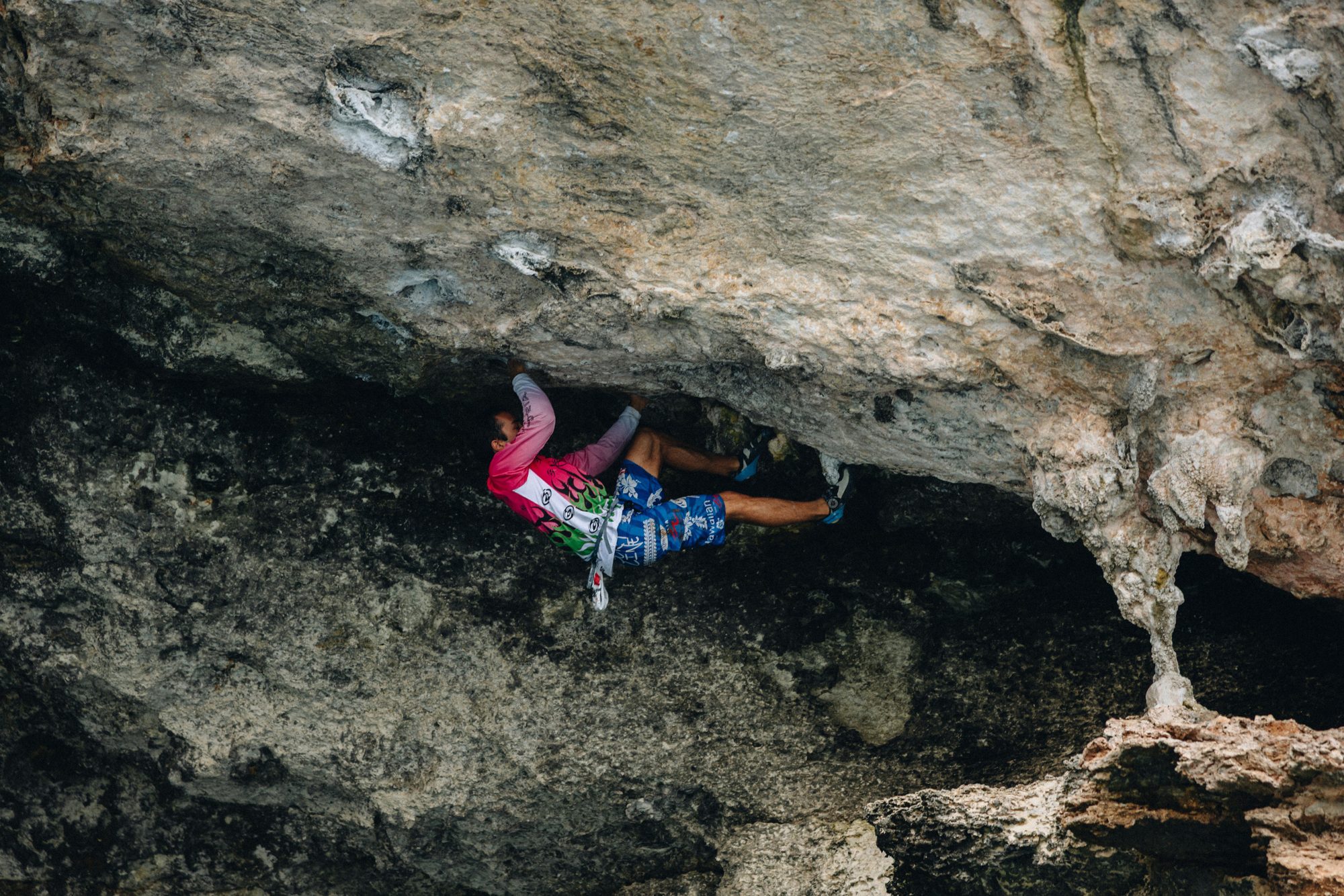 Climber in a pink top on an overhanging limestone cave